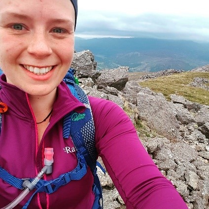 Rebecca smiling at the camera at the top of a hill